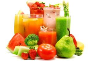glasses of juice surrounded by vegetables and fruits